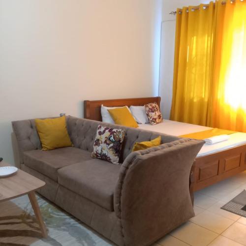 a living room with a couch with yellow pillows at Kendy’s Cozy Haven in Mombasa