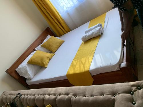 a bedroom with a bed with a yellow blanket and a couch at Kendy’s Cozy Haven in Mombasa