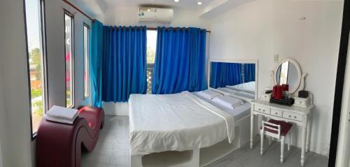a bedroom with a bed with blue curtains and a mirror at Hotel MAI TUAN Chánh Môn A in Tây Ninh
