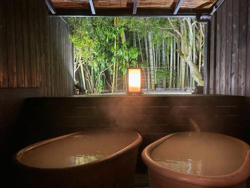 a room with two tubs in a room with trees at Mount View Hakone in Hakone