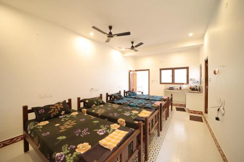 a room with three beds and a kitchen in it at Le Pondy Home Stay in Pondicherry