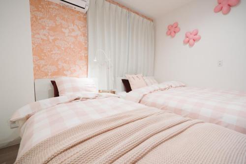 two beds in a room with pink flowers on the wall at Shinjuku Mermaid Apartment in Tokyo