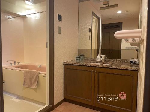 a bathroom with a tub and a sink and a mirror at NK BLD4F Sapporo 3LDK 3BR 1 floor 1 room in Sapporo