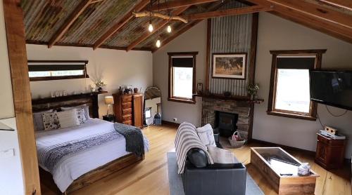 a bedroom with a large bed and a fireplace at Baroona Cottage in Barwite
