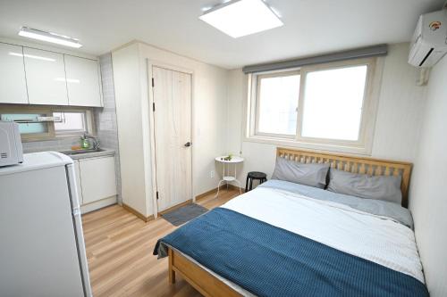 a small bedroom with a bed and a kitchen at Sunnyhill Guesthouse Hongdae in Seoul