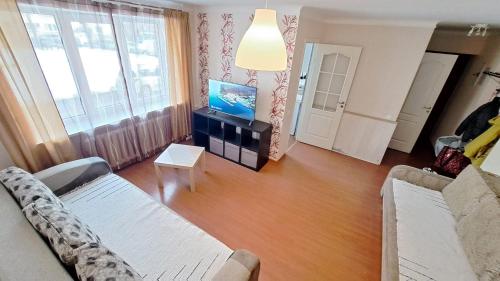 Una sala de estar con un sofá y un televisor. en Teatra 32, en Daugavpils