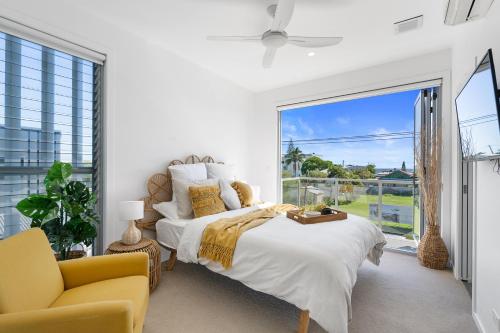 Un dormitorio con una cama, una silla y una ventana en Oceanviews on Pearl, en Kingscliff