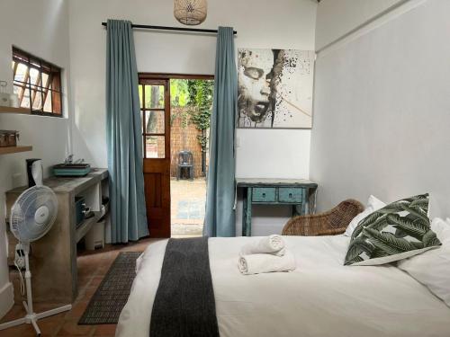 a bedroom with a bed and a desk and a door at Guesthouse @ 31 Murray in Pretoria