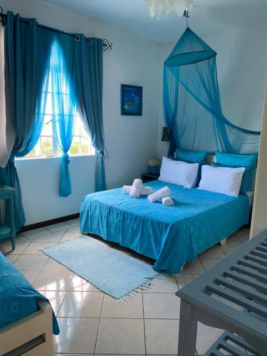 niebieska sypialnia z łóżkiem z niebieskimi zasłonami w obiekcie Résidence Bleu Azur w mieście Grand Baie