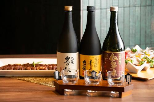 three bottles of wine sitting on a table with glasses at Hotel Ichibata in Matsue