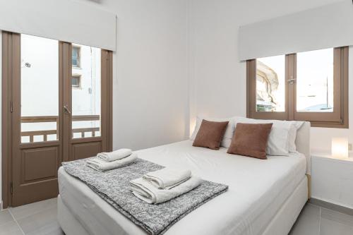 a bedroom with a white bed with towels on it at Cozy Comfy Town House in Naxos Chora