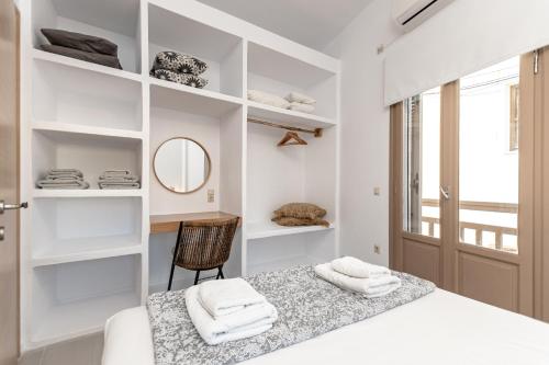 a white bedroom with a bed and a mirror at Cozy Comfy Town House in Naxos Chora