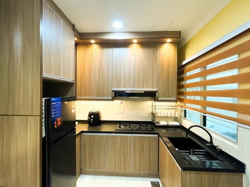a kitchen with a black refrigerator and wooden cabinets at SK Homestay Seremban 2 in Seremban