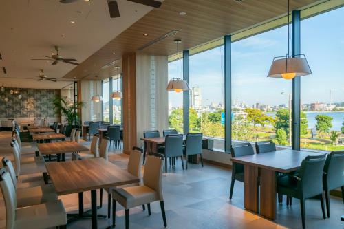 um restaurante com mesas e cadeiras e janelas grandes em Hotel Ichibata em Matsue