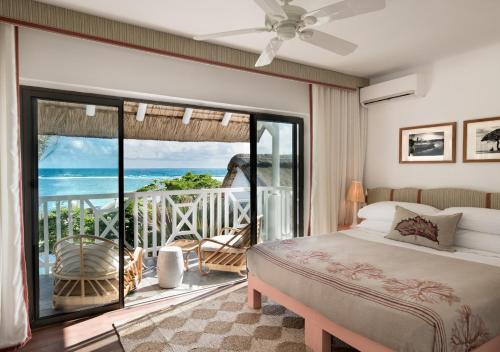a bedroom with a bed and a balcony with the ocean at La Maison d'Eté Hotel by NEWMARK in Poste Lafayette