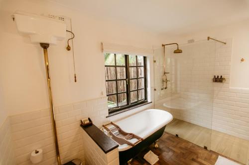 a white bathroom with a tub and a window at Amanzi Lodge in Harare