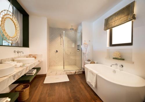 een badkamer met 2 wastafels, een bad en een douche bij La Maison d'Eté Hotel by NEWMARK in Poste Lafayette