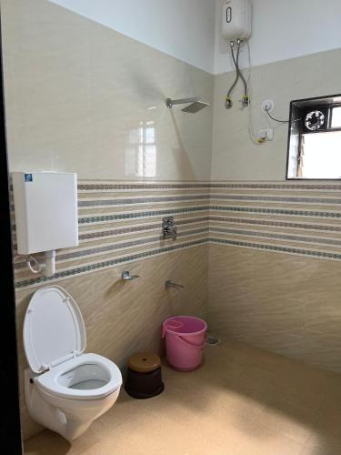 a bathroom with a toilet and a pink bucket at iIRA Stays: Ocean Bliss (Sea View) in Alibaug