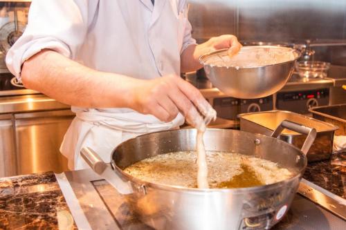 a man in a kitchen preparing food in a pot at Hotel Ichibata in Matsue