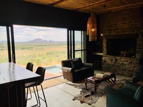 a living room with a table and a chair and a fireplace at LEOPARD'S VIEW MOUNTAIN VILLA @ Steinheim Game Farm & Camping in Prospect