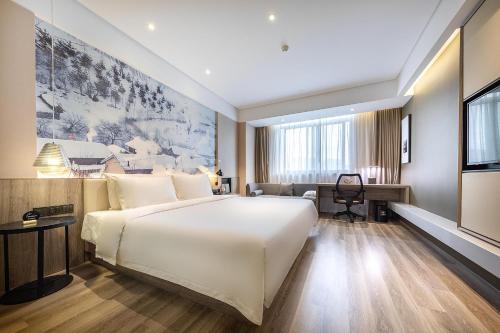 a bedroom with a large white bed and a desk at Atour Hotel Hongqiao Hub National Exhibition Center Shanghai in Shanghai