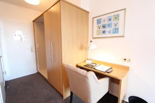 a room with a desk with a chair and a cabinet at Hotel Thormählen in Lübeck