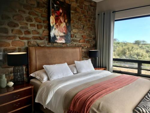 a bedroom with a large bed and a stone wall at LEOPARD'S VIEW MOUNTAIN VILLA @ Steinheim Game Farm & Camping in Prospect