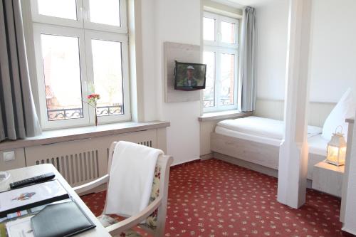 a small room with a bed and two windows at Hotel Thormählen in Lübeck