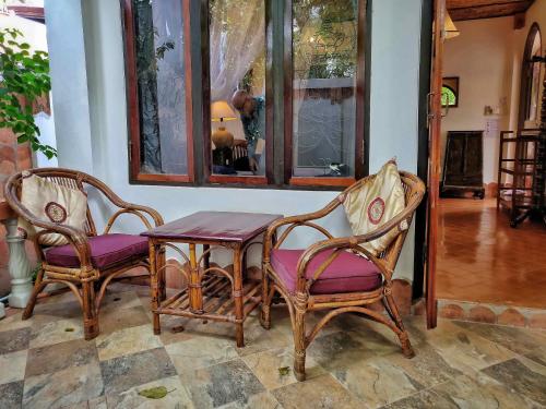 Mut Mee Garden Guest House في نونغ خاي: طاولة وكرسيين وطاولة مع مقاعد أرجوانية