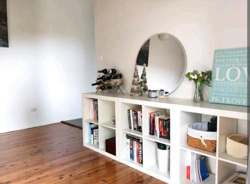 a white book shelf with a mirror and books at Stylish Master Suite + Private Bathroom + TV FREE Parking Pet Friendly in Glenfield