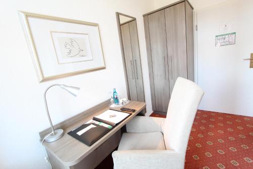 a room with a desk with a chair and a lamp at Hotel Thormählen in Lübeck