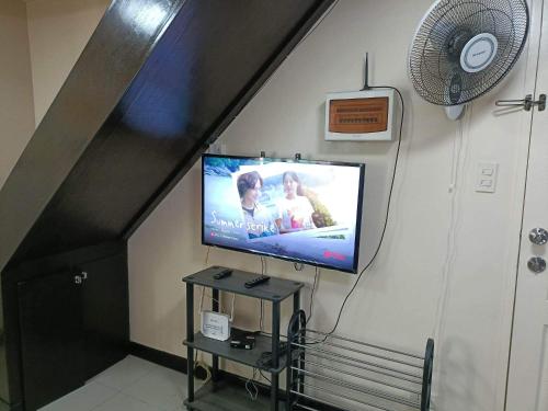 Une télévision à écran plat est installée sur un mur avec un escalier. dans l'établissement Lovely home away from home, à Manille
