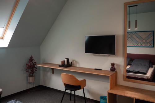 a room with a desk with a television and a chair at Bornemisza Kúria Wellness Resort in Tiszabecs