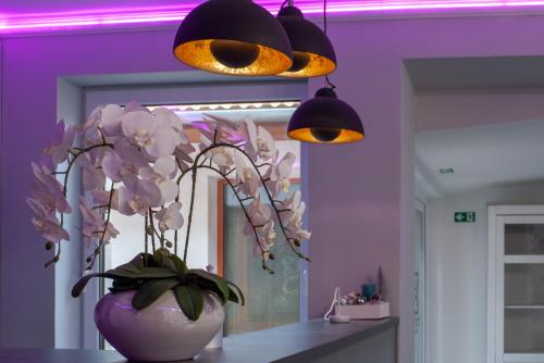 a vase of flowers on a table with two lights at Bornemisza Kúria Wellness Resort in Tiszabecs