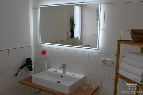a bathroom with a sink and a mirror and towels at Ferienwohnungen in Losheim am See - Gästehaus am Bachlauf - in Losheim