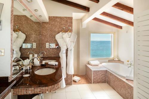 a bathroom with a large tub and a sink and a bath tubermott at Hotel Le Maquis in Porticcio