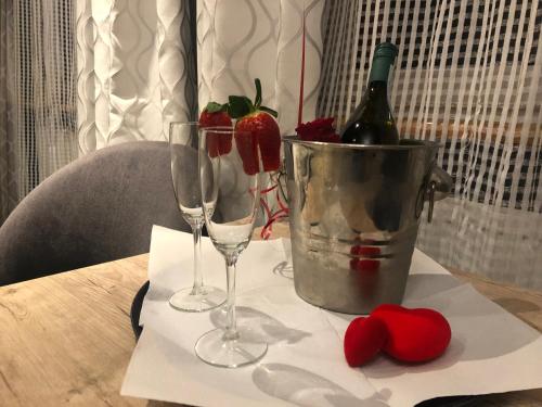 a table with two wine glasses and a bucket of strawberries at Sosnowe Zacisze in Białystok