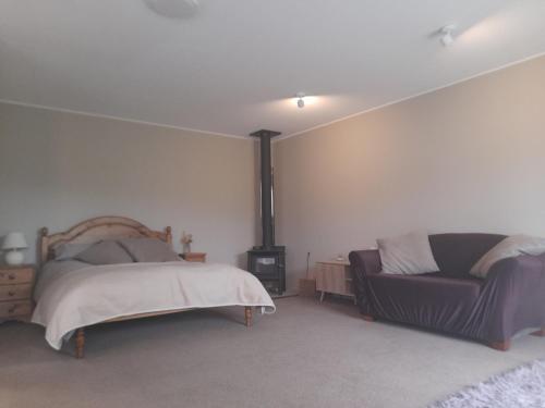 a bedroom with a bed and a couch at One bedroom country cottage in Motueka