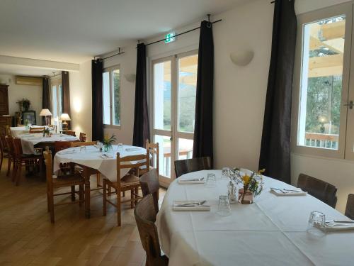 un restaurante con mesas y sillas blancas y una ventana en auberge de tesa, en Occhiatana