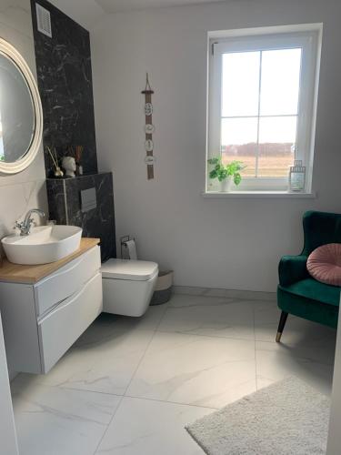 a bathroom with a sink and a toilet and a window at Apartament Kendal in Dźwirzyno