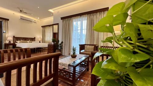 een woonkamer met een grote groene plant op de voorgrond bij Rosewood By The Beach Goa in Benaulim