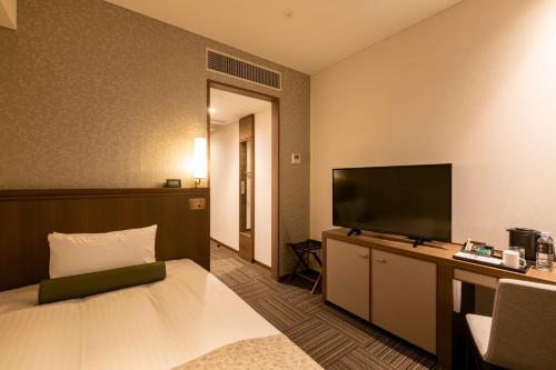 a hotel room with a bed and a flat screen tv at Hotel Ichibata in Matsue