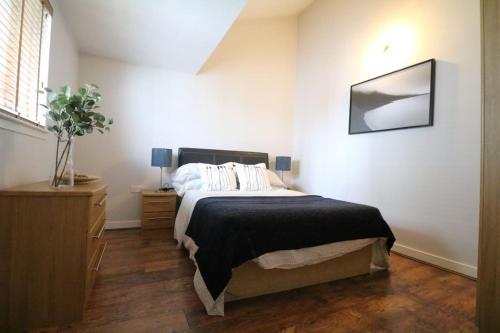 a bedroom with a bed and a dresser and a window at Lovely Modern Central & Spacious in Liverpool