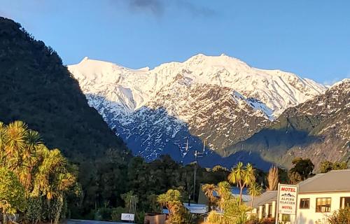 a snow covered mountain in front of a town at Kea Retreat in Franz Josef