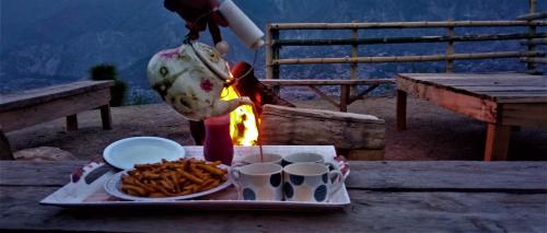 a person is cooking food on a table with a tray of food at Adults Only! Kashmir Eagle Heights Cottage & Restaurant by LMC in Muzaffarabad