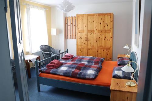 a bedroom with an orange bed with a plaid blanket at Pension Lotte in Kühlungsborn