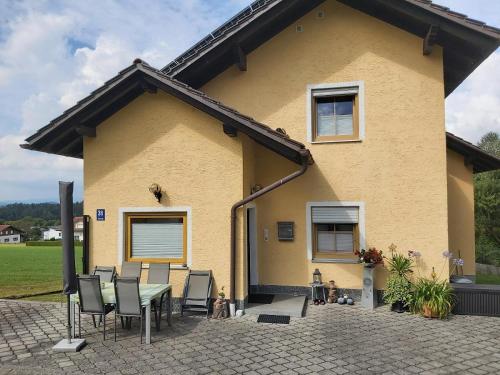 een geel huis met een tafel en stoelen bij Ferienwohnung Elisabeth Biebl in Neuschönau