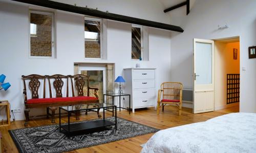 1 dormitorio con 1 cama, 2 sillas y vestidor en La Quinta, belle maison en pierres avec jardins, en Asnelles