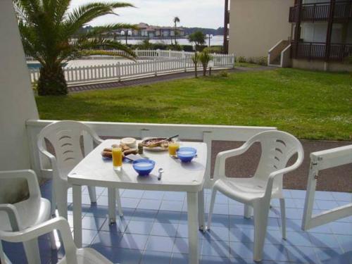 une table et des chaises blanches avec de la nourriture dans l'établissement Appartements à côté Lac Marin de Port d'Albret, à Vieux-Boucau-les-Bains