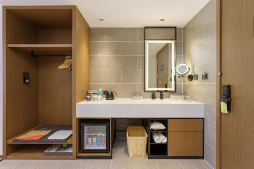 ein Bad mit einem Waschbecken und einem Spiegel in der Unterkunft Atour Hotel Dalian Airport in Dalian